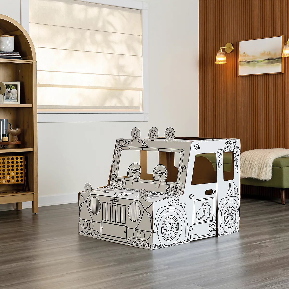 Ein Papp-Jeep-Spielhaus steht in einem Zimmer. Der Jeep ist mit Stiften bemalbar.