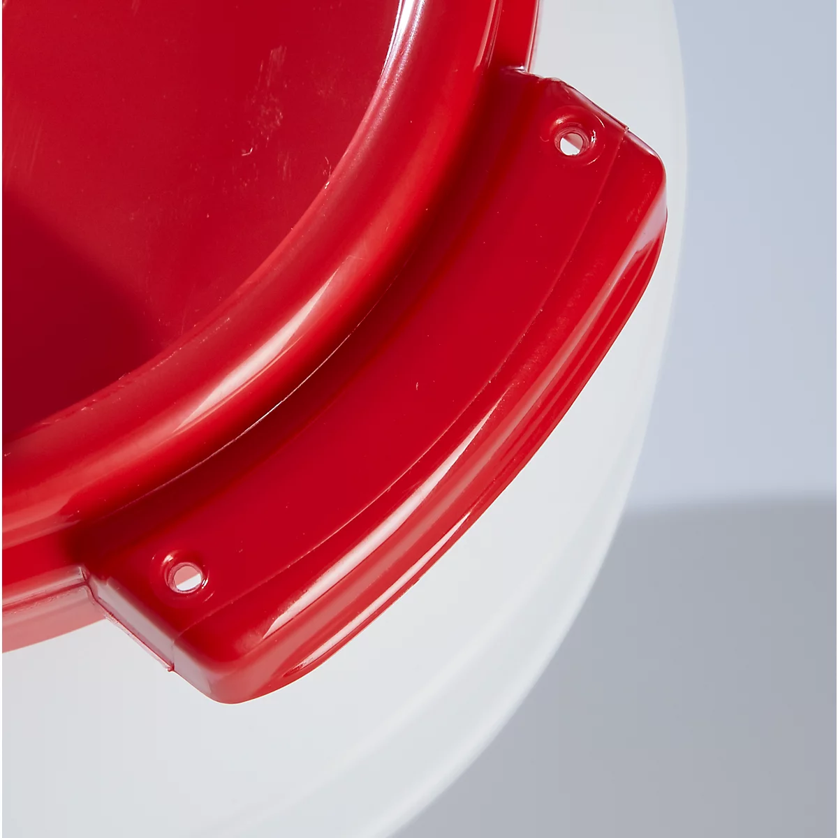 Gros plan d'une poignée rouge sur un récipient blanc, deux trous.