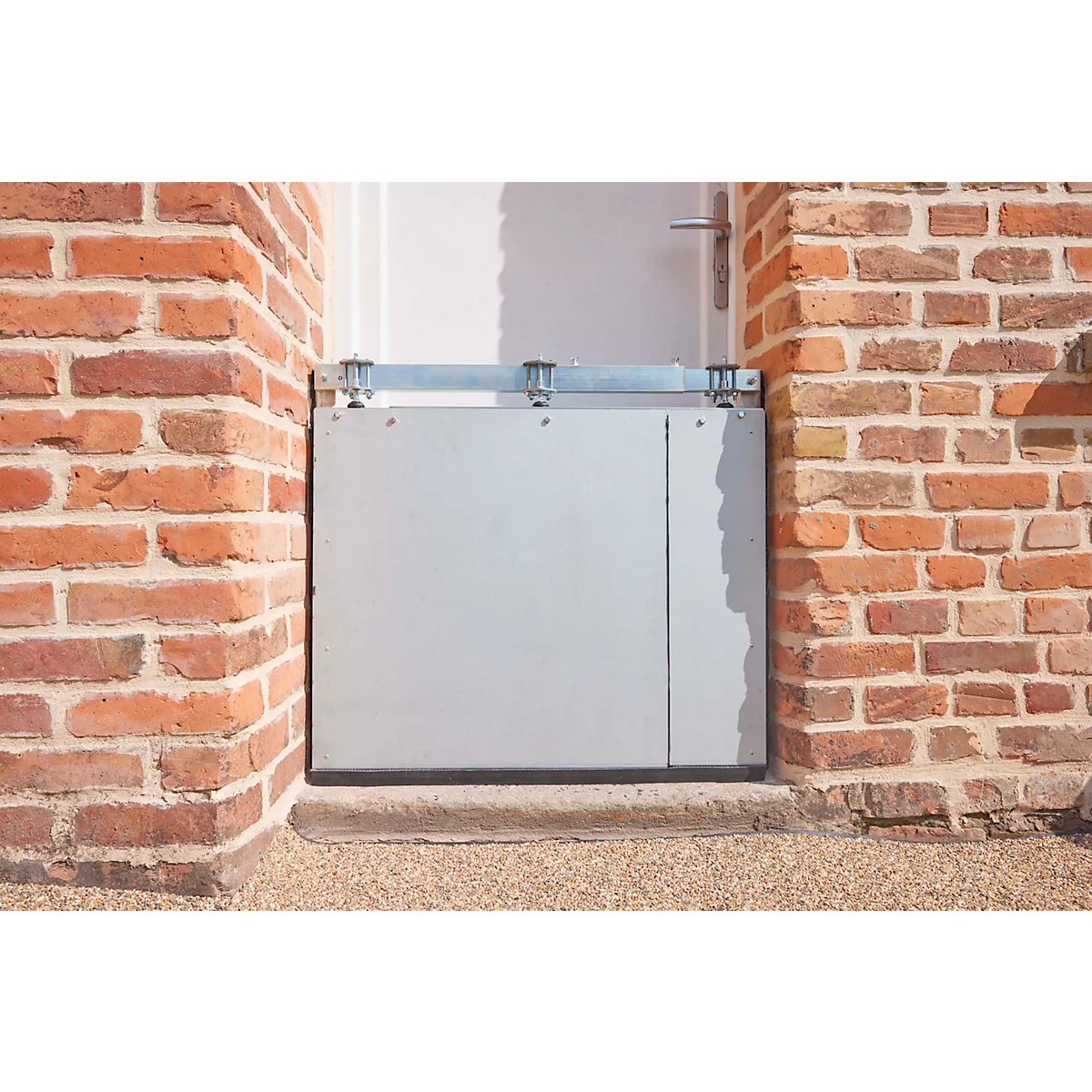 Blocage de porte gris entre des murs en briques. Au-dessus de la porte se trouve un support métallique.
