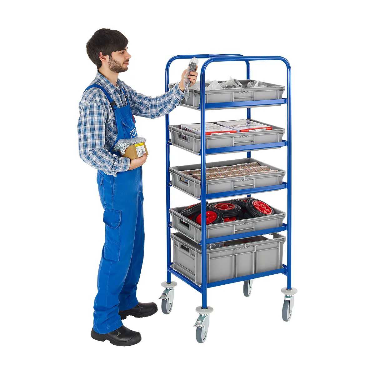 A man in blue overalls reaching into a box on a blue trolley. Grey plastic crates with tools and spare parts.
