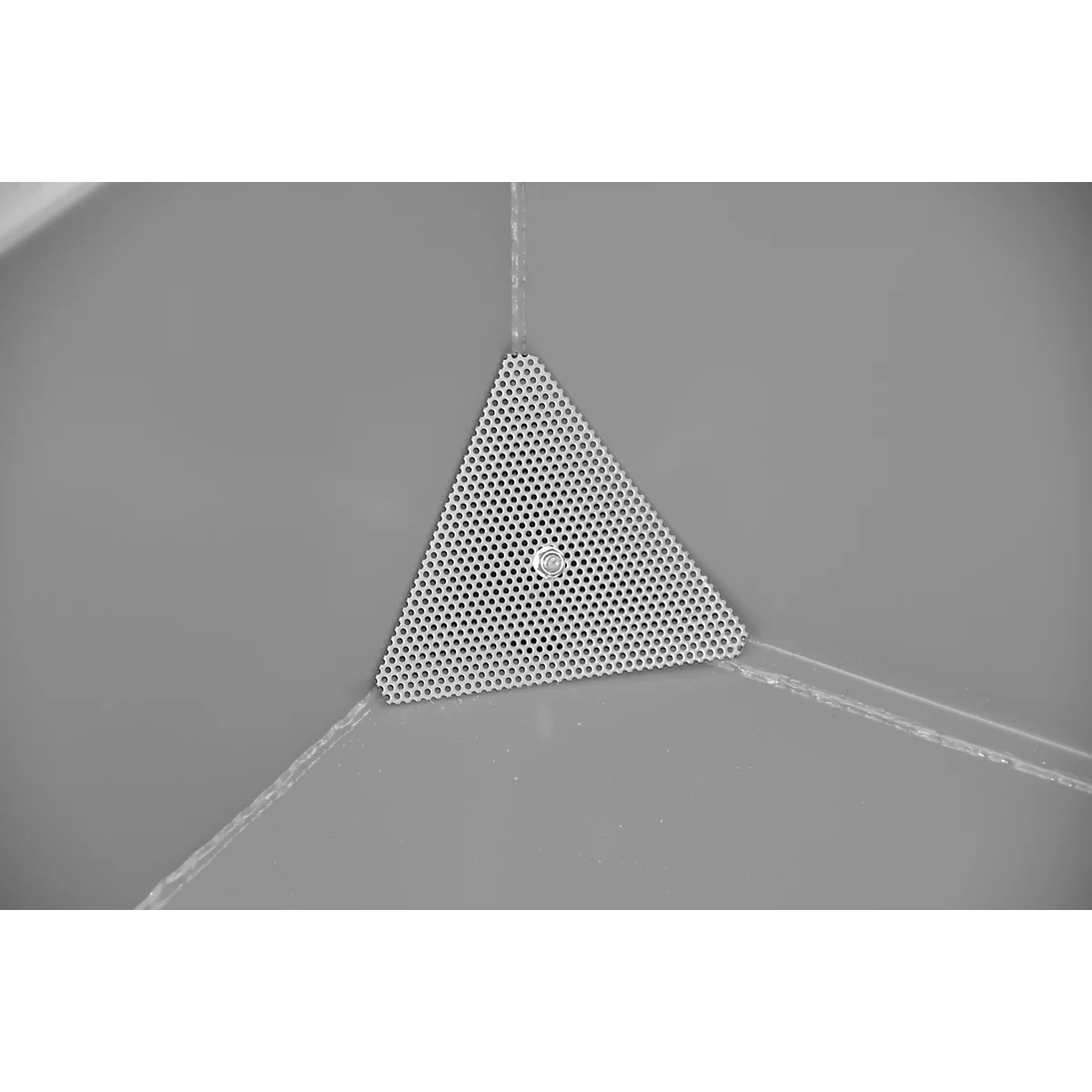 Gros plan en niveaux de gris d'un triangle perforé avec une vis au milieu, posé sur une surface grise.
