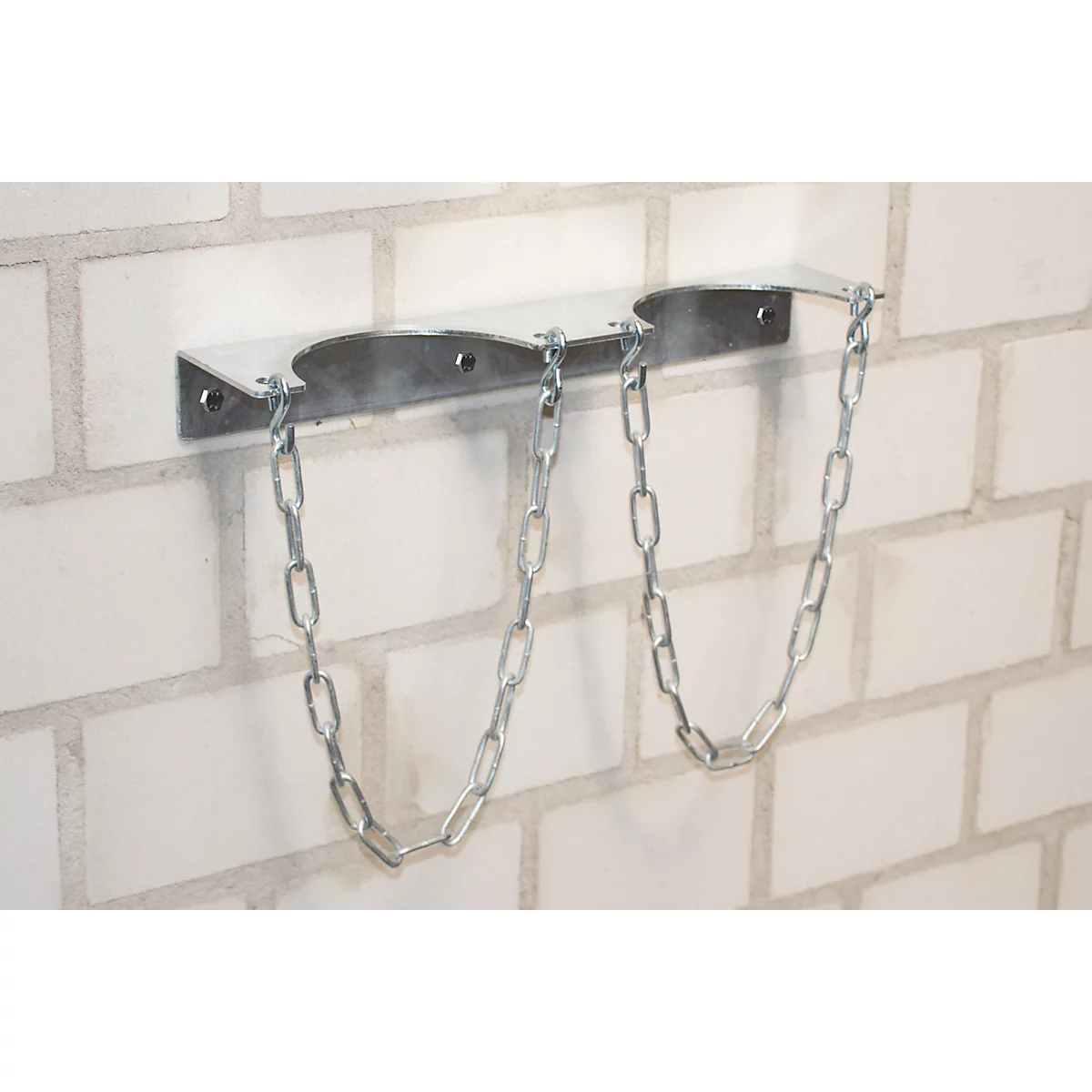 Metal bracket with chains on white brick wall. Probably holds two gas cylinders.