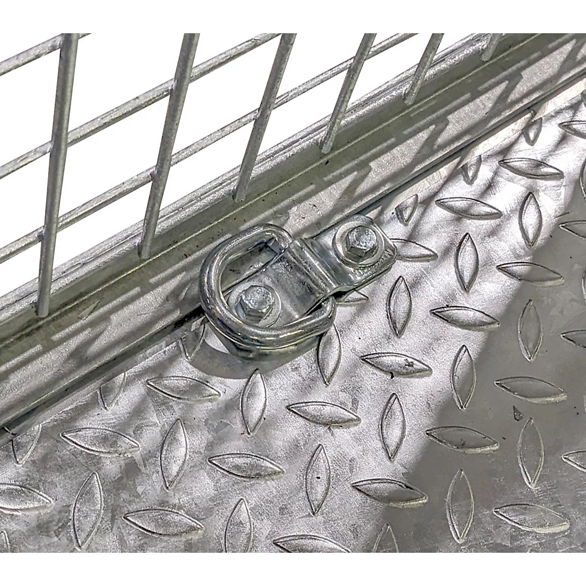 Nahaufnahme einer Metallkonstruktion: Gitter, Diamantblech und ein D-Ring zur Befestigung.