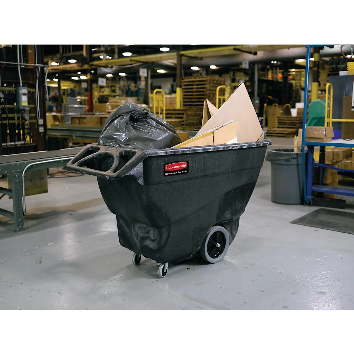 Chariot de transport noir avec sac poubelle et cartons. Environnement d'usine en arrière-plan.