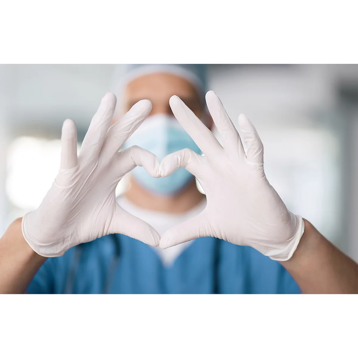 Een persoon in medische kleding vormt een hart met gehandschoende handen. Het gezicht en de operatiekleding zijn op de achtergrond aangegeven.