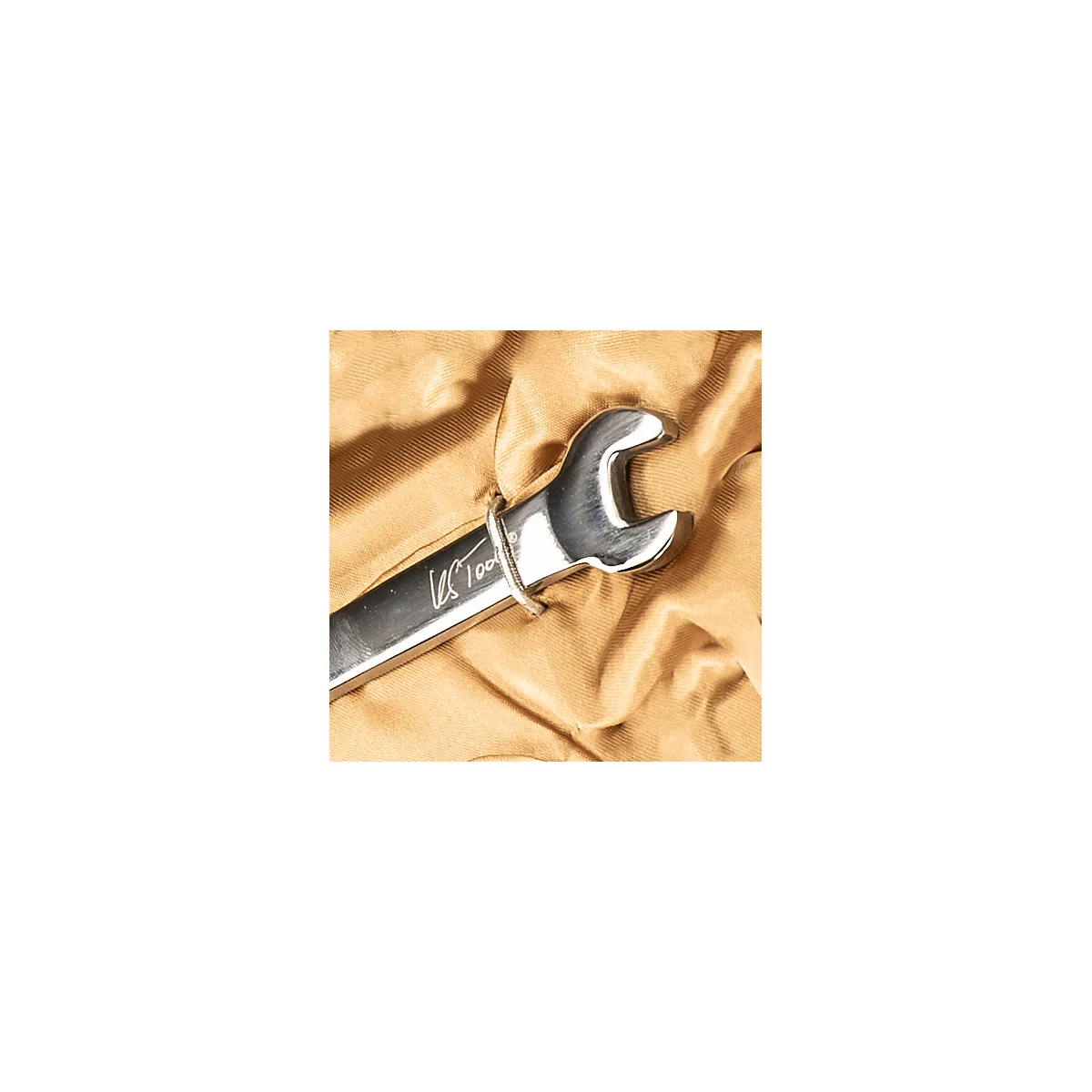 Nahaufnahme eines glänzenden Schraubenschlüssels auf beigem Stoff. Auf dem Werkzeug ist "US Tools 100" eingraviert.