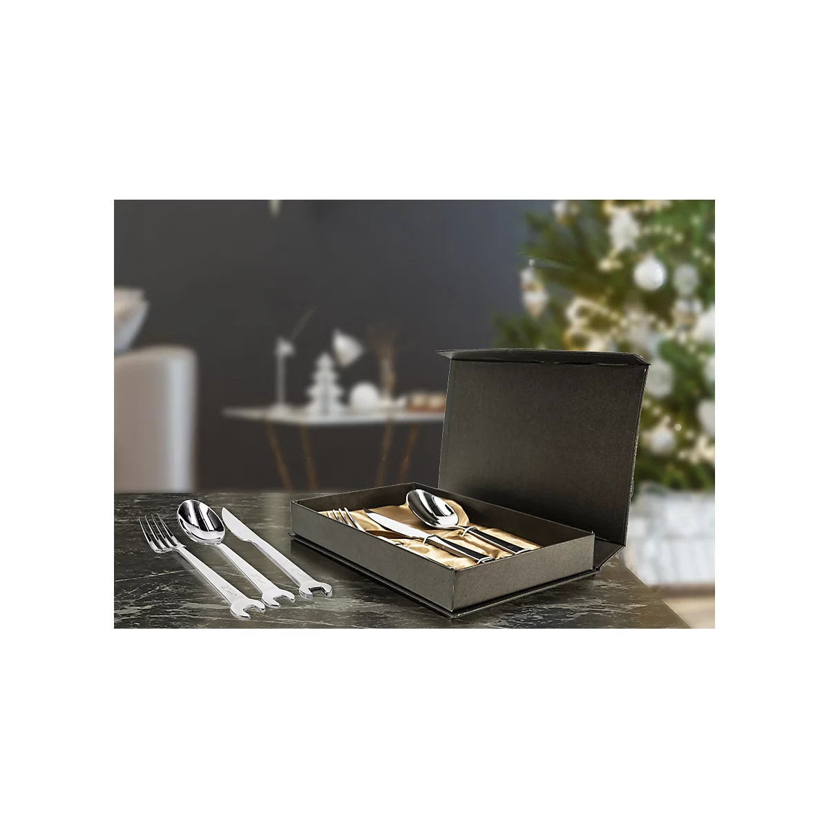 Besteckset in schwarzer Box, vor verschwommenem Hintergrund. Gabeln, Löffel und Messer glänzen.