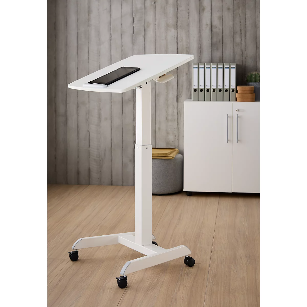 Witte, in hoogte verstelbare statafel met tablet. Wieltjes, bureau en achtergrond zijn licht.
