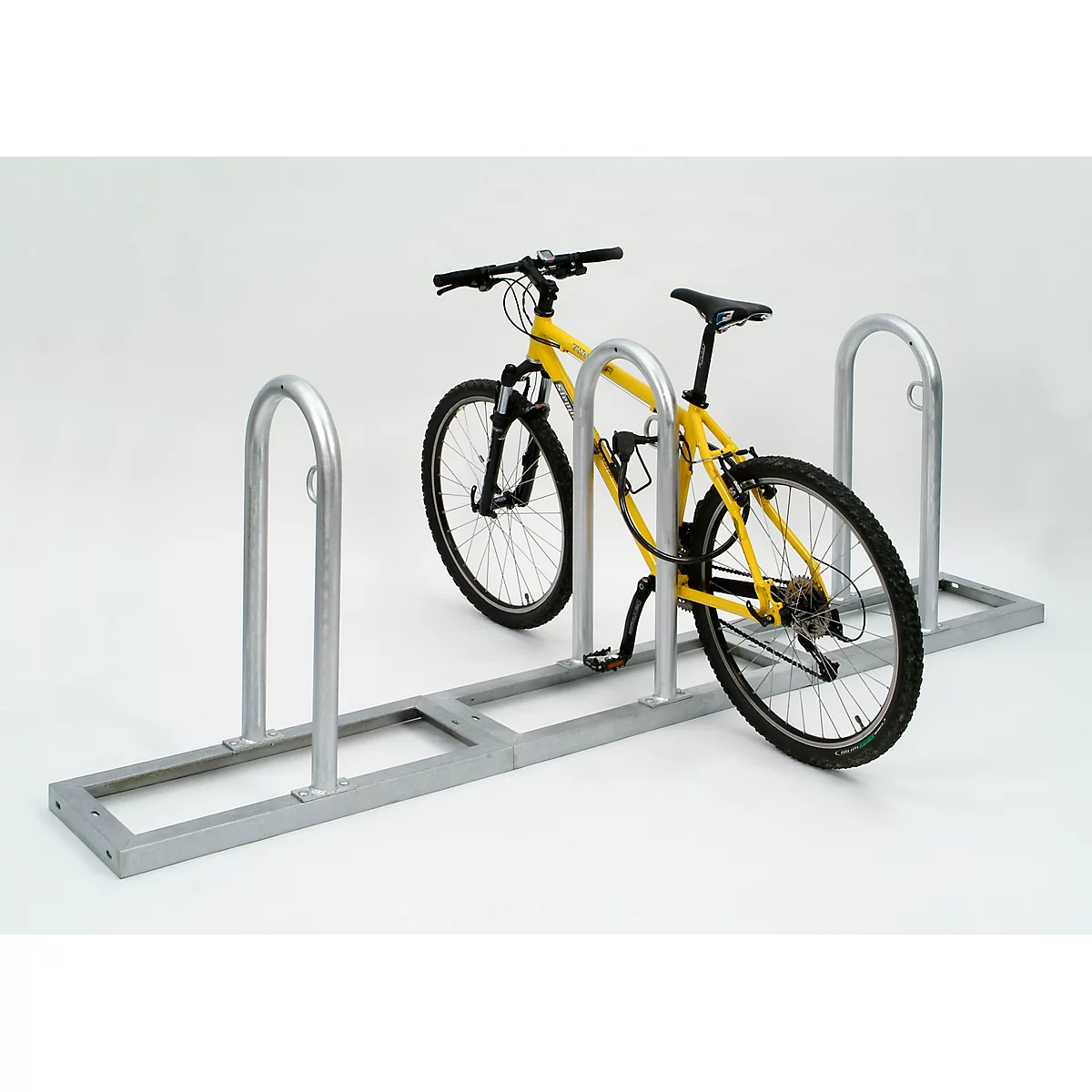 Yellow bicycle in a bike rack. The setting is bright and neutral.