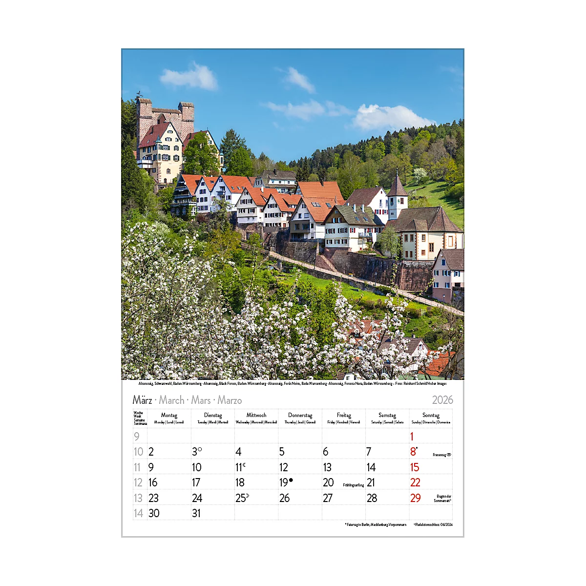 Ein Kalender mit einem idyllischen Blick auf eine malerische Stadt mit Fachwerkhäusern und einer Burg. Der blaue Himmel und die blühenden Bäume verstärken die Atmosphäre.