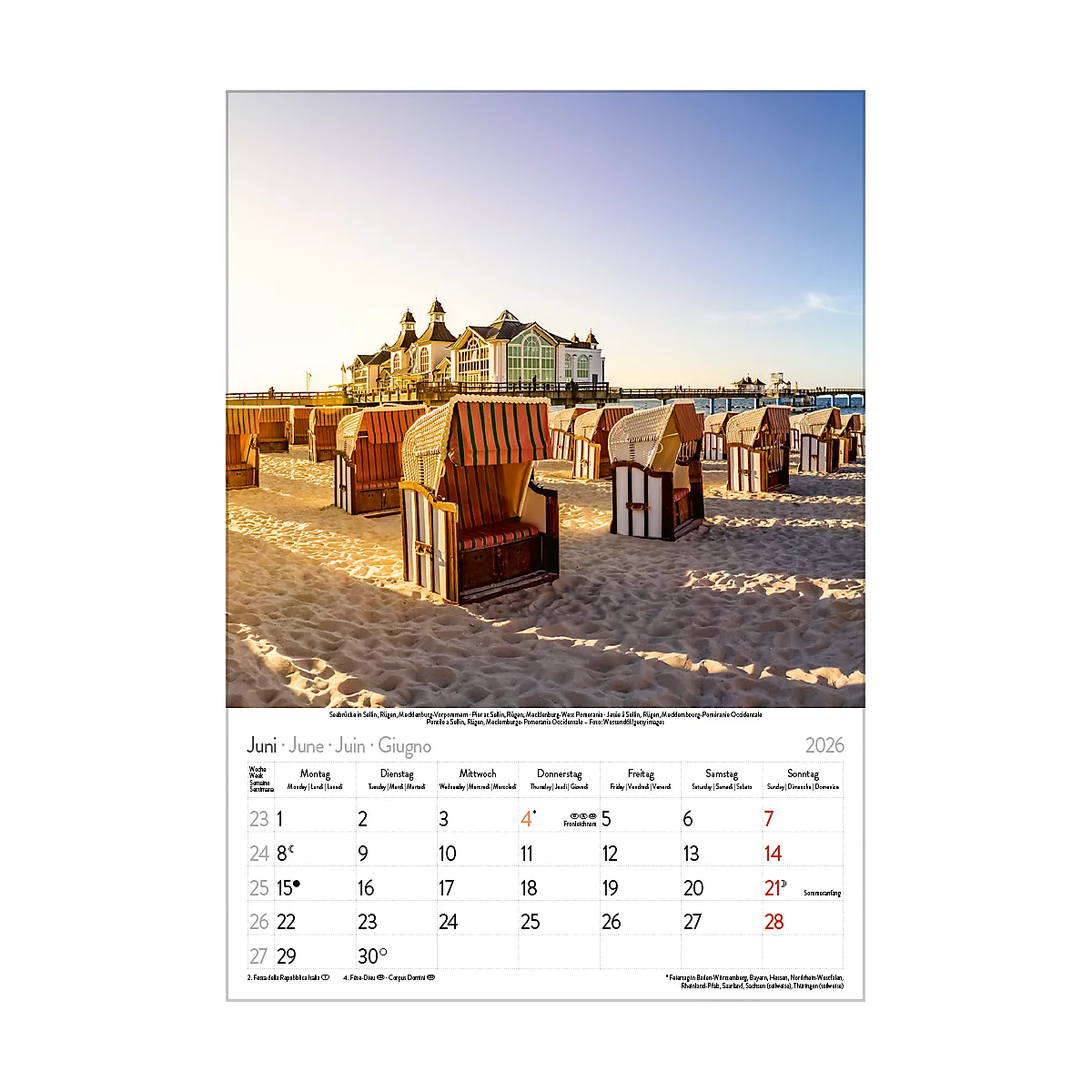 Strandkörbe am Strand, im Hintergrund ein Pier und ein Gebäude, Sonnenschein und blauer Himmel, Kalender Juni 2026.