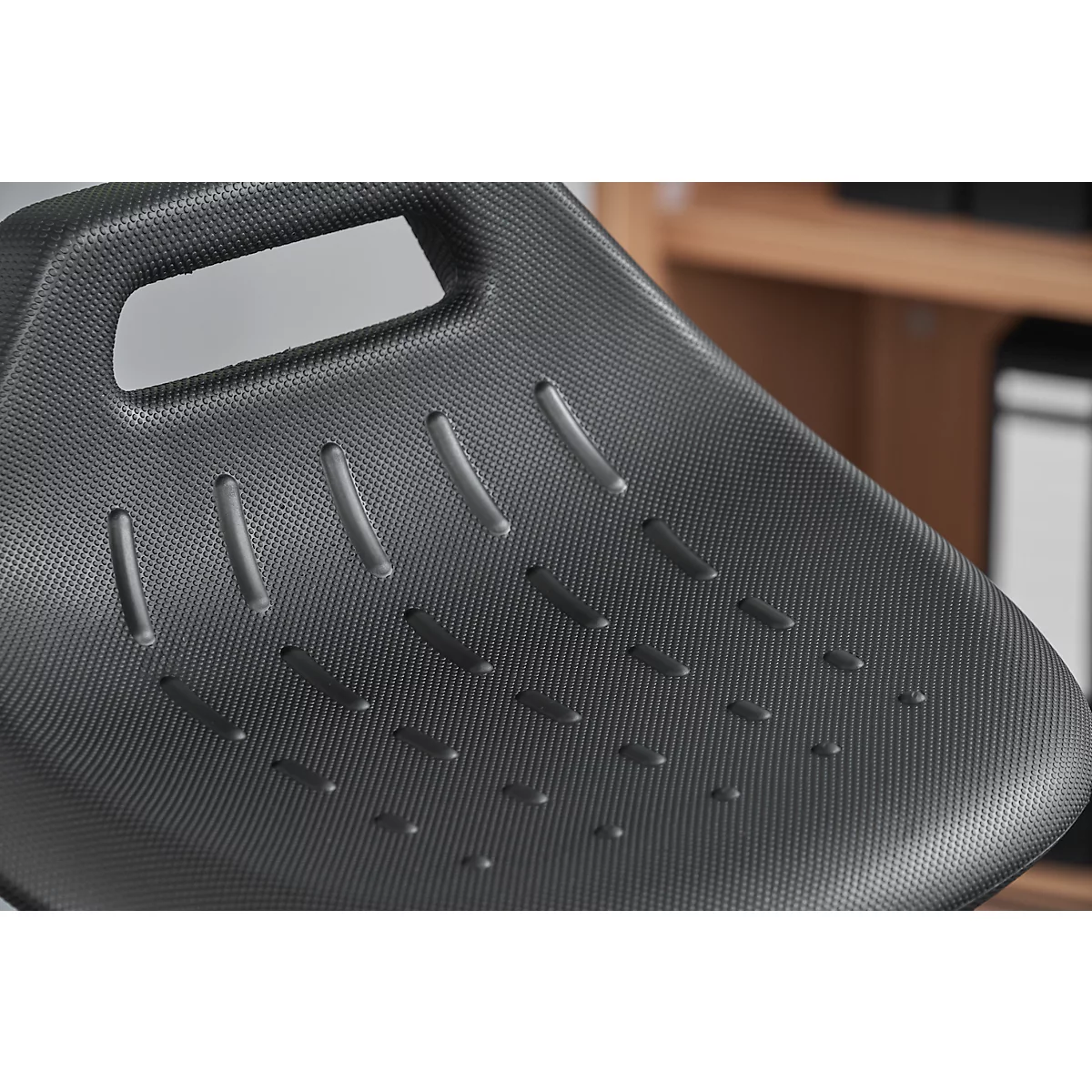 Close-up of the black seat of an office chair, featuring ventilation slots and a handle opening.