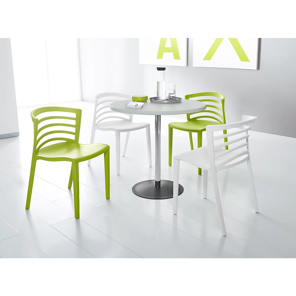 Vier moderne Stühle in Apfelgrün und Weiß um einen runden Tisch in einem hellen, minimalistischen Raum.