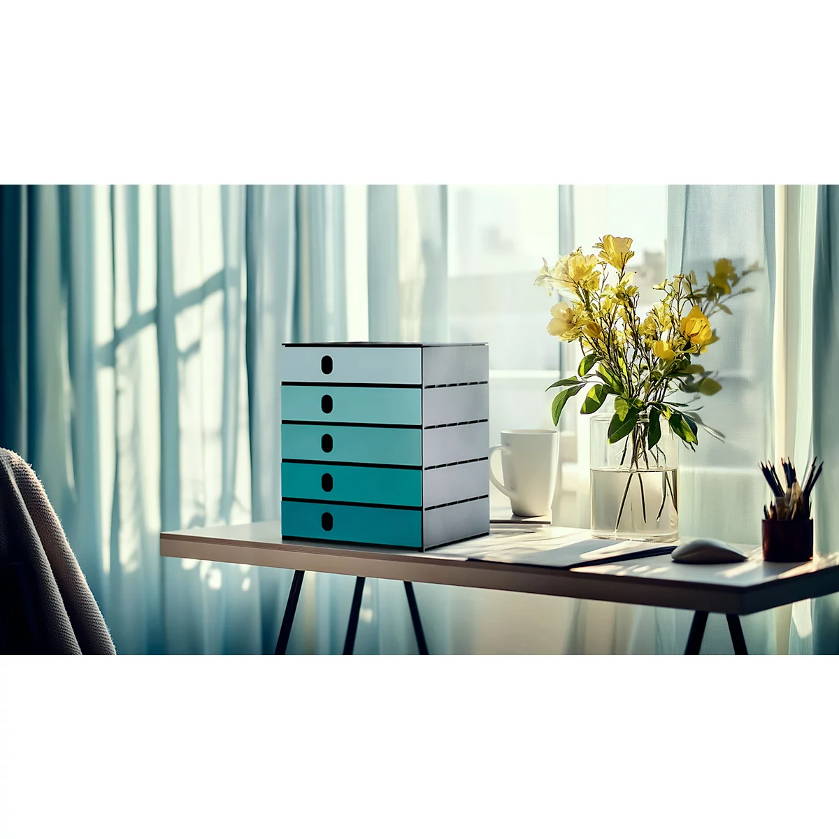 Bureau avec système de tiroirs turquoise, fenêtre en arrière-plan. A côté, un vase avec des fleurs jaunes.