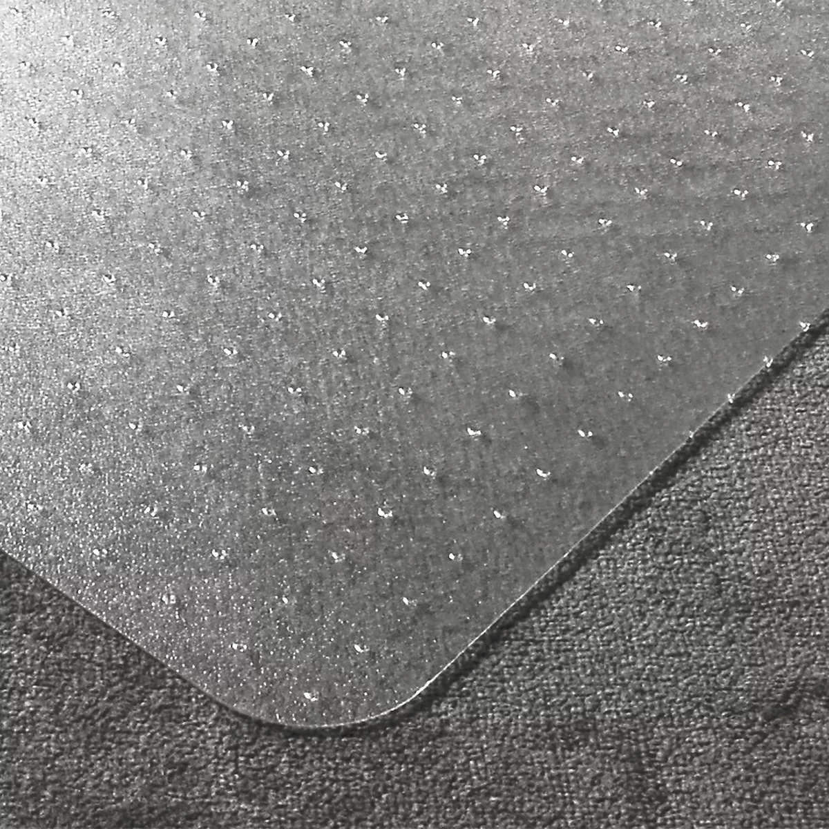 Transparente Bodenschutzmatte auf einem grauen Teppich, mit kleinen Noppen auf der Unterseite.