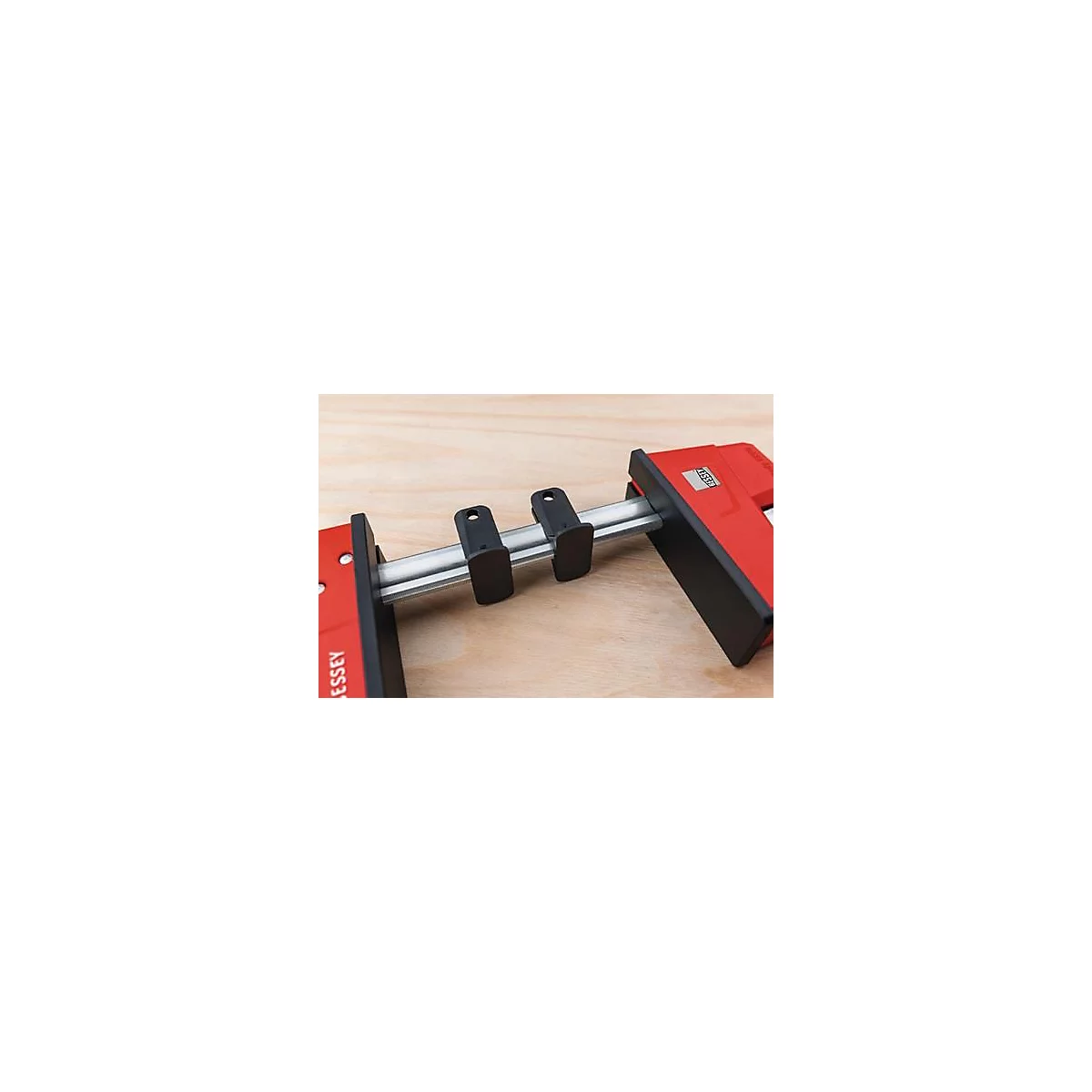 Red clamp with black elements on a wooden surface. The tool is marked with the name "BESSEY".