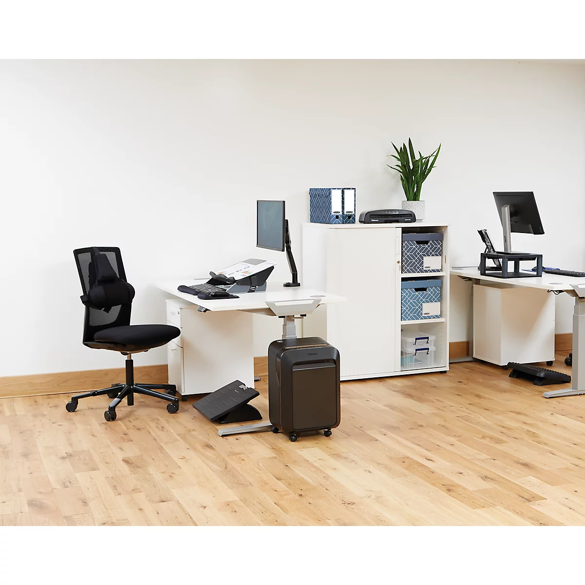 Bureau avec bureau, chaise, destructeur de documents et plantes. Le sol est en bois.