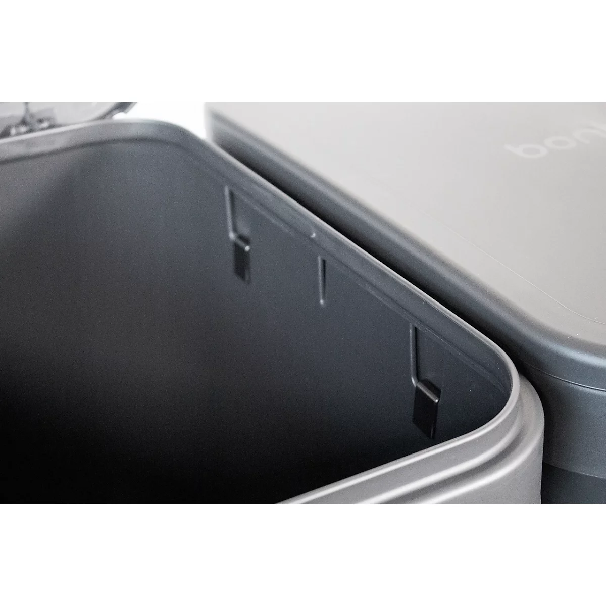 Gros plan sur deux récipients gris avec couvercles. Les surfaces sont lisses et monochromes.