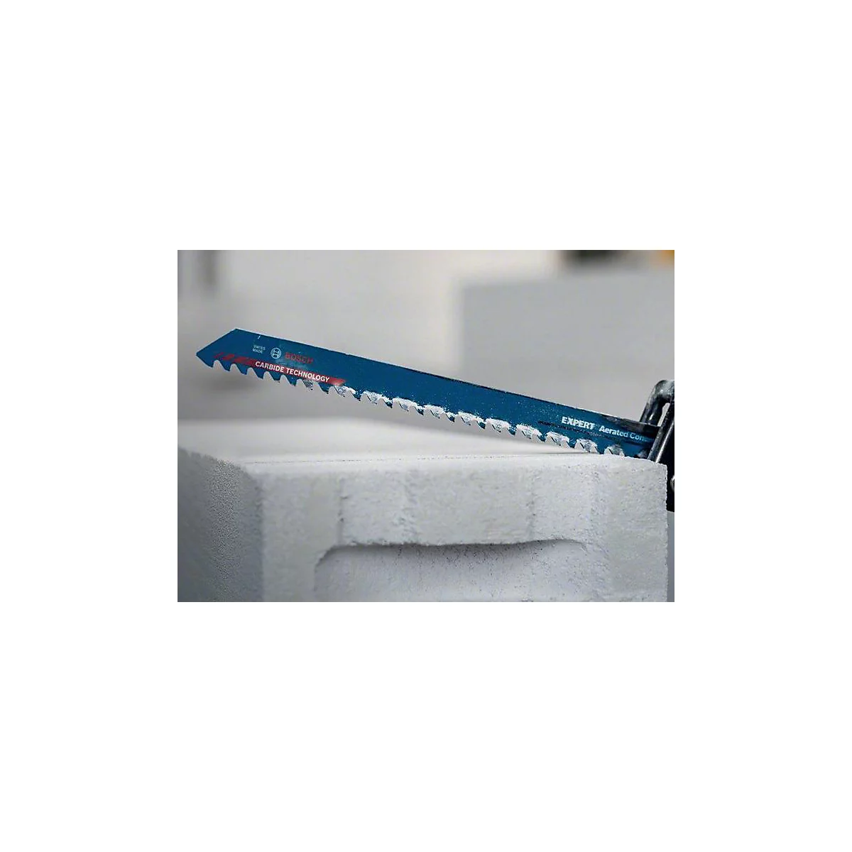 Blaue Säge mit Zacken schneidet weißen Porenbetonblock. Aufschrift: Carbide Technology.
