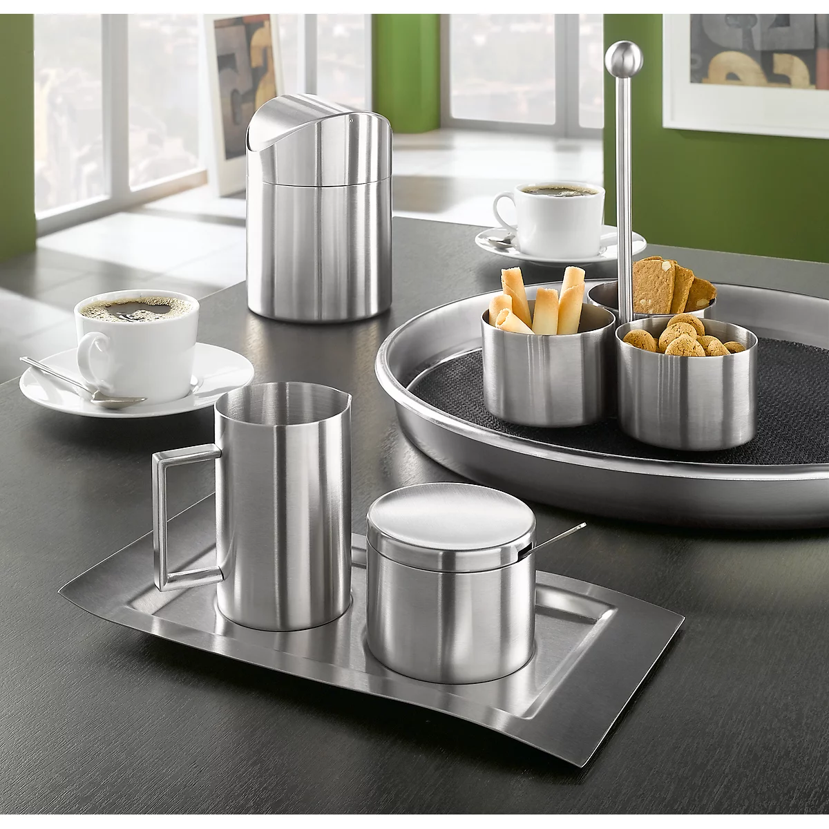 Stainless steel coffee service with cups, sugar bowl, and serving dishes, all set on a table.