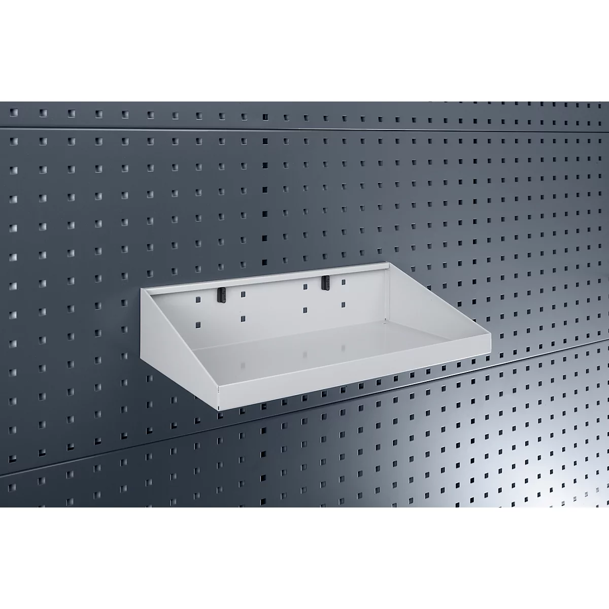 Weisses Regalboden an einer grauen Lochwand. Das Regal hat eine abgeschrägte Front.