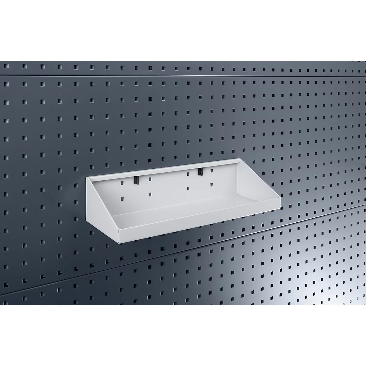 Weiße Metallablage an einer grauen Lochwand. Die Ablage hat eine schräge Vorderseite.