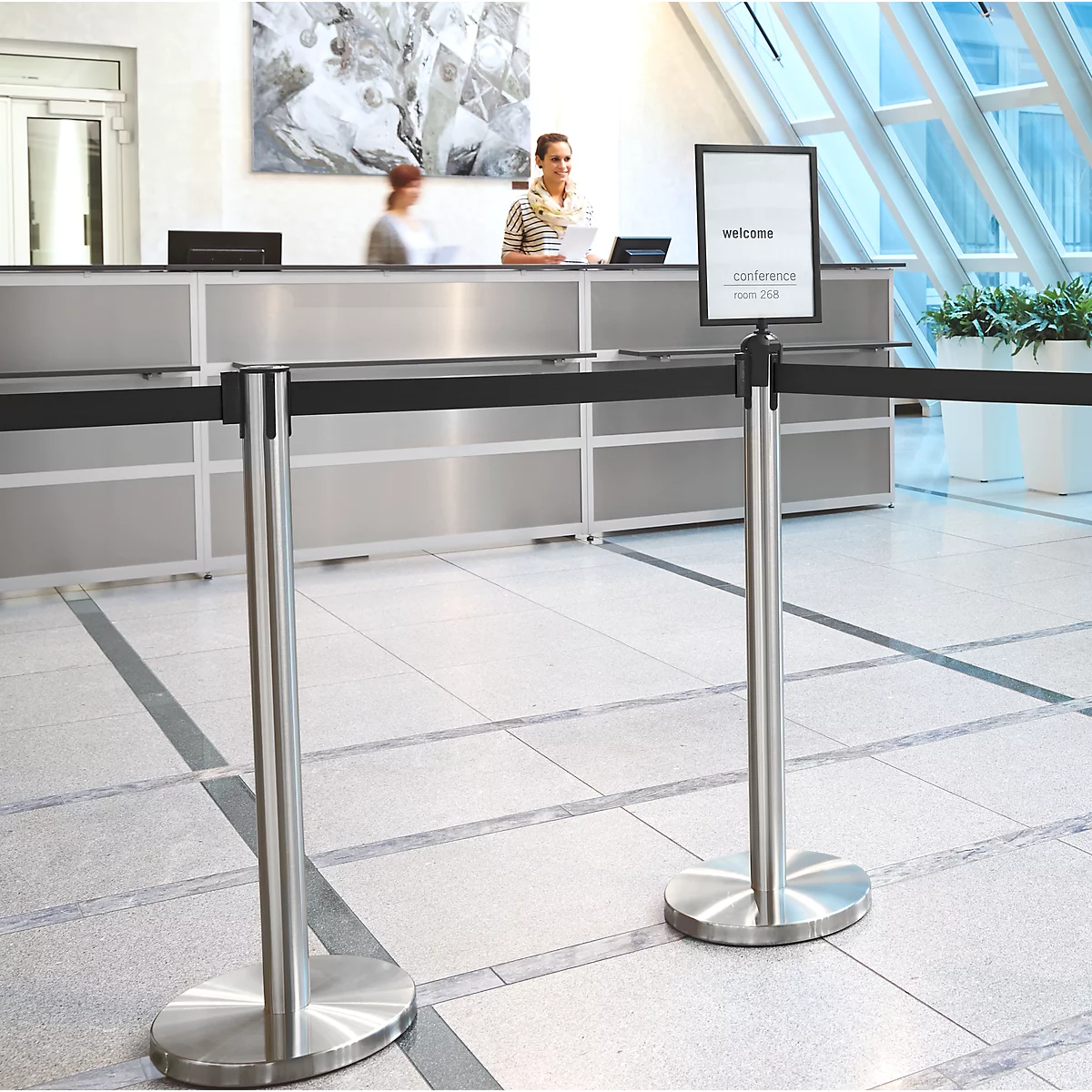 Reception with welcome sign, barrier tape, and staff. Bright, modern lobby.