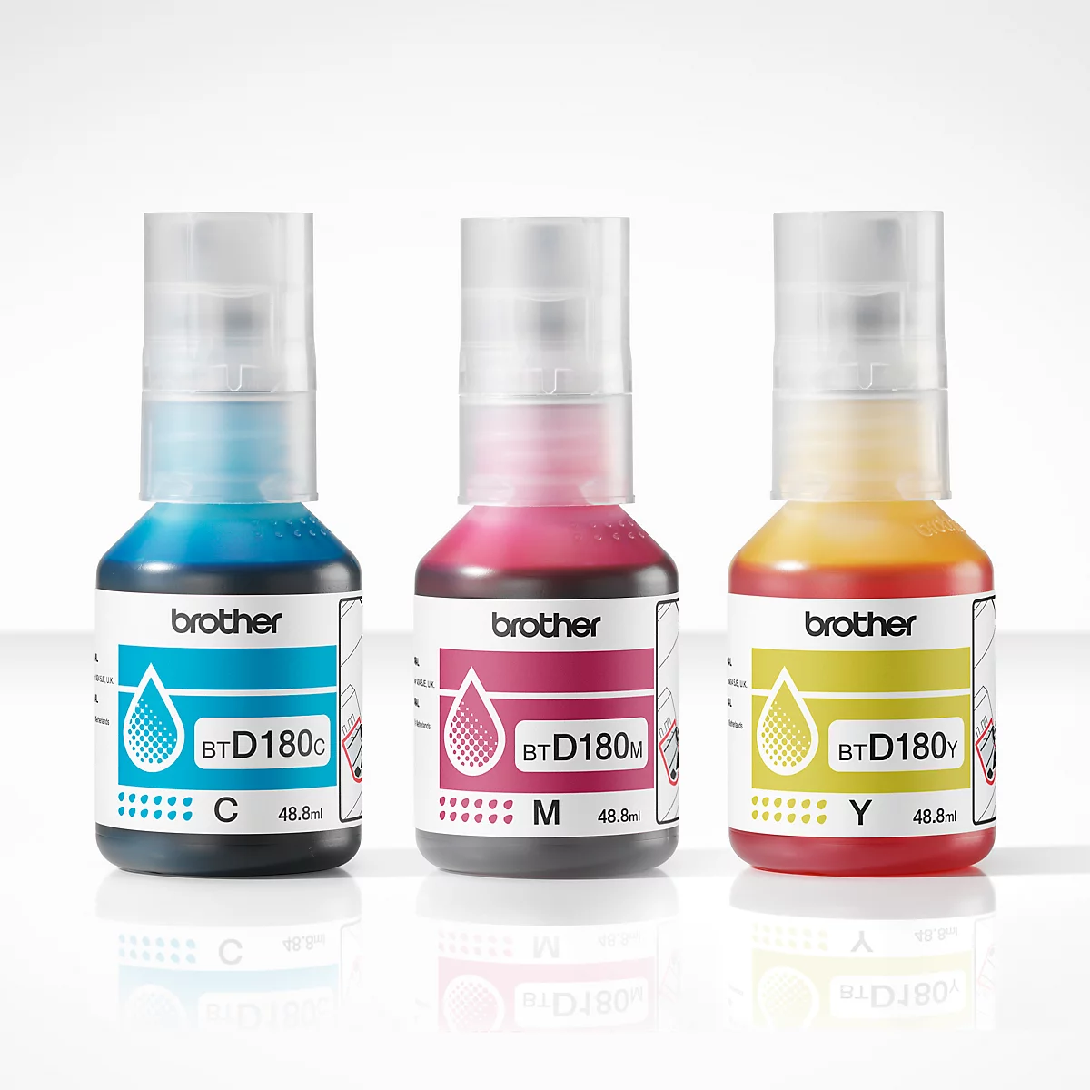 Trois bouteilles d'encre Brother: Bleu, magenta, jaune. Étiquetées avec des lettres et un numéro de volume. Bouchons transparents.