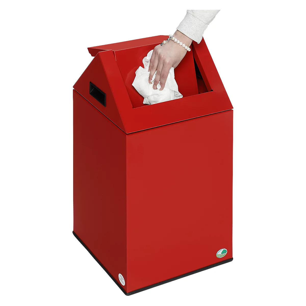 A hand is throwing a white cloth into a red trash can. The bin has a slanted top.