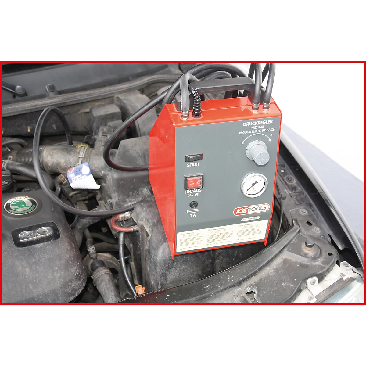 Ein rotes, graues Gerät zur Druckregulierung im Motorraum eines Autos.
