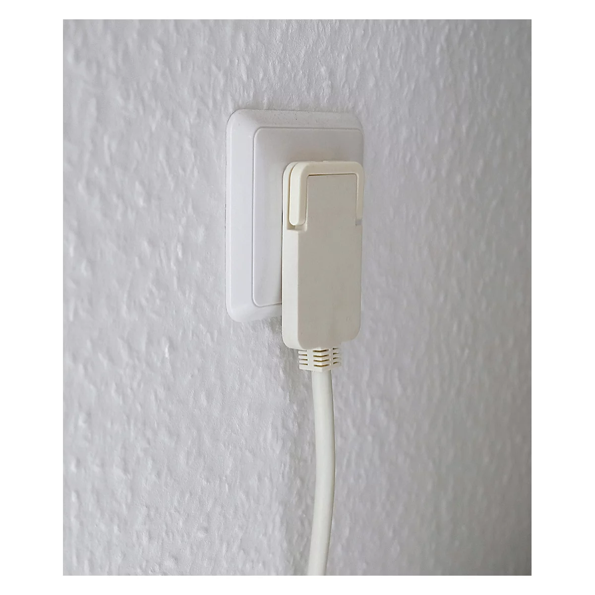 Prise de courant avec adaptateur branché et câble sur mur blanc.