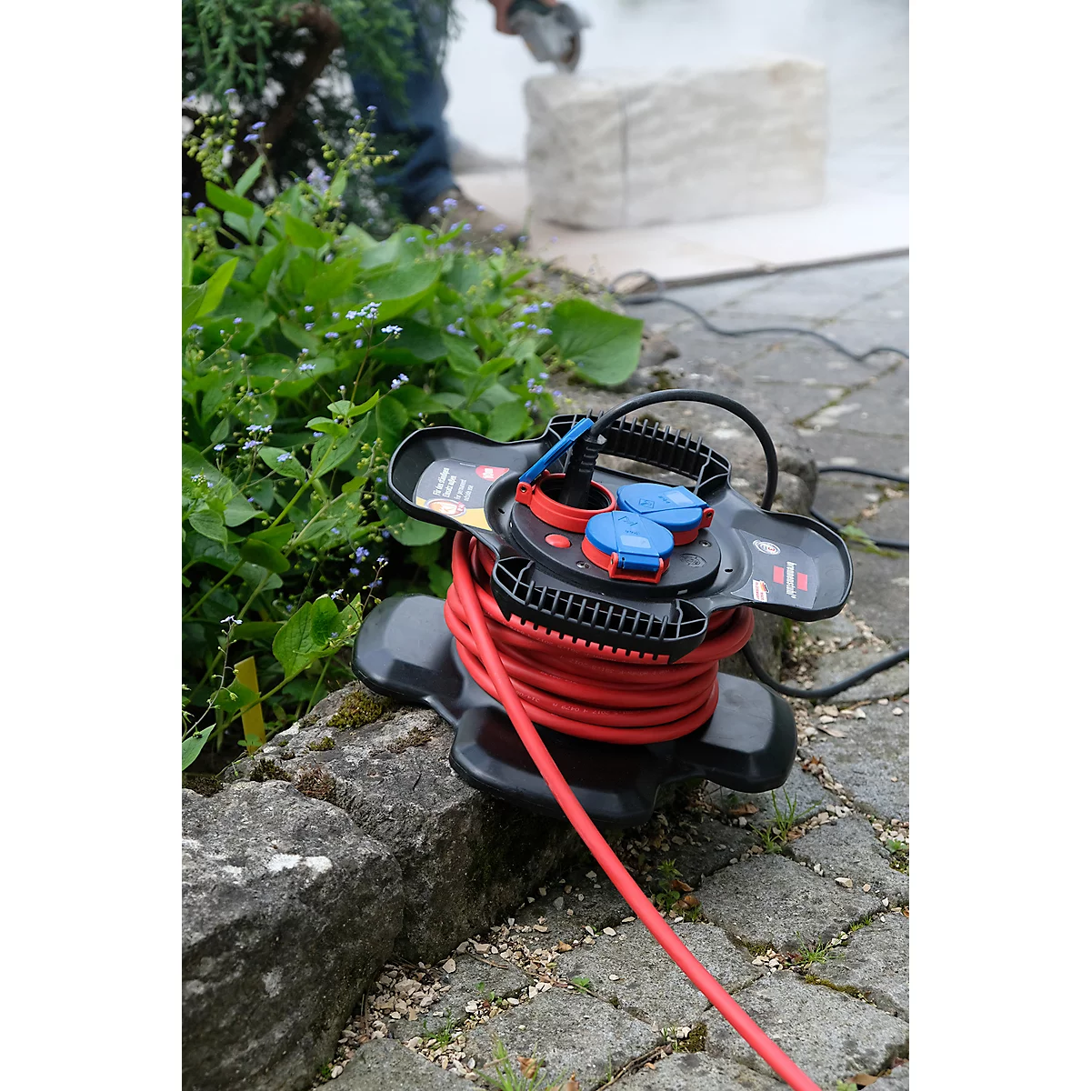 Une bobine de câble rouge est sur la pierre, à l'arrière-plan de la pierre est sciée.