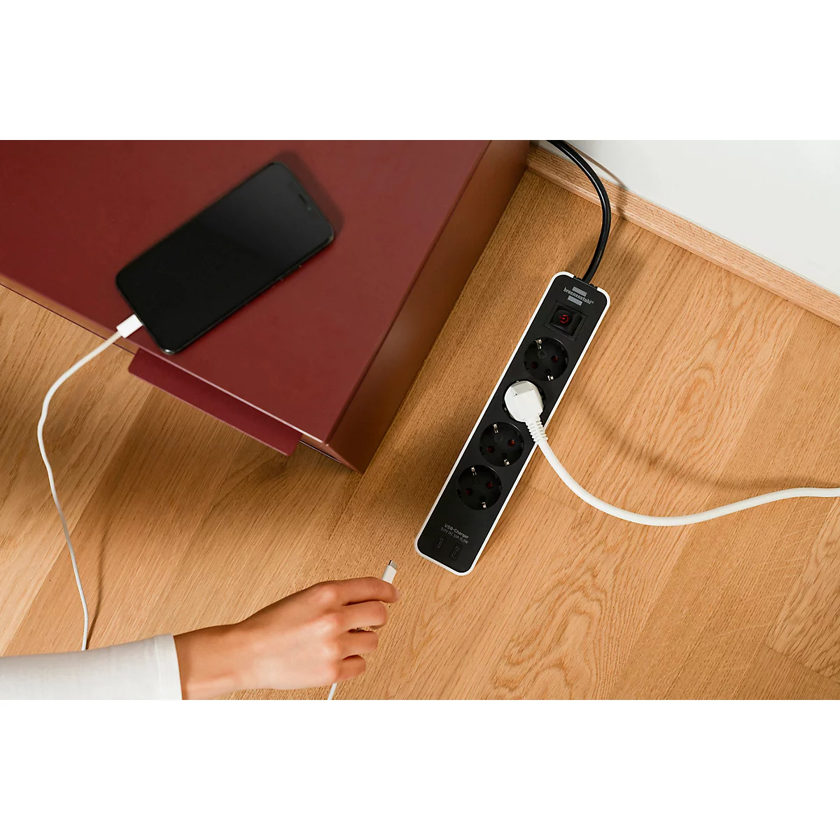 Gros plan sur une multiprise blanche avec deux prises. Un interrupteur marche/arrêt noir avec marquage rouge est visible.