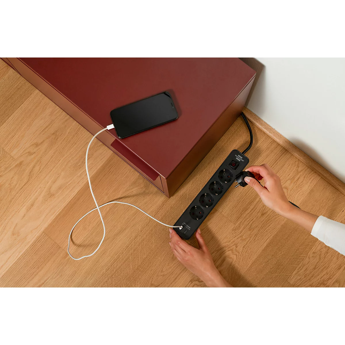 Zwart verlengsnoer met vier stopcontacten, aan/uit-schakelaar en USB-poorten. Kabel links.
