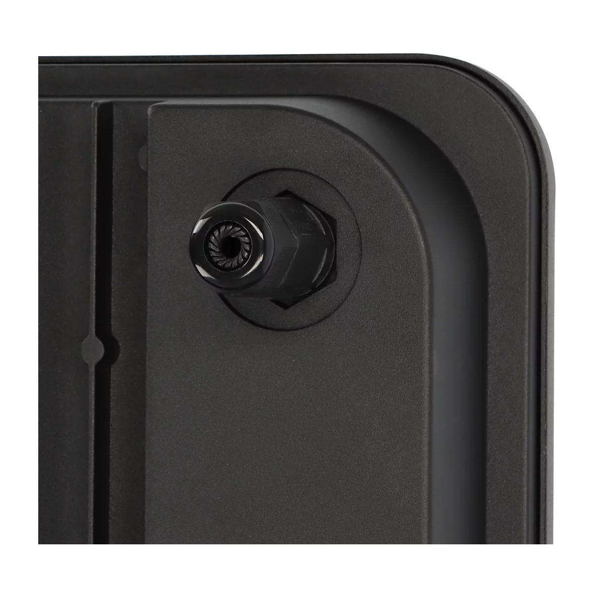 Ein LED-Fluter beleuchtet einen Zaun. Dunkle Umgebung mit grünen Blättern.