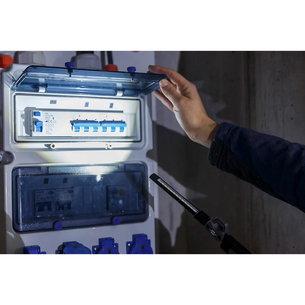 Appareil technique noir avec poignée et port de charge. Une lumière verte est allumée.