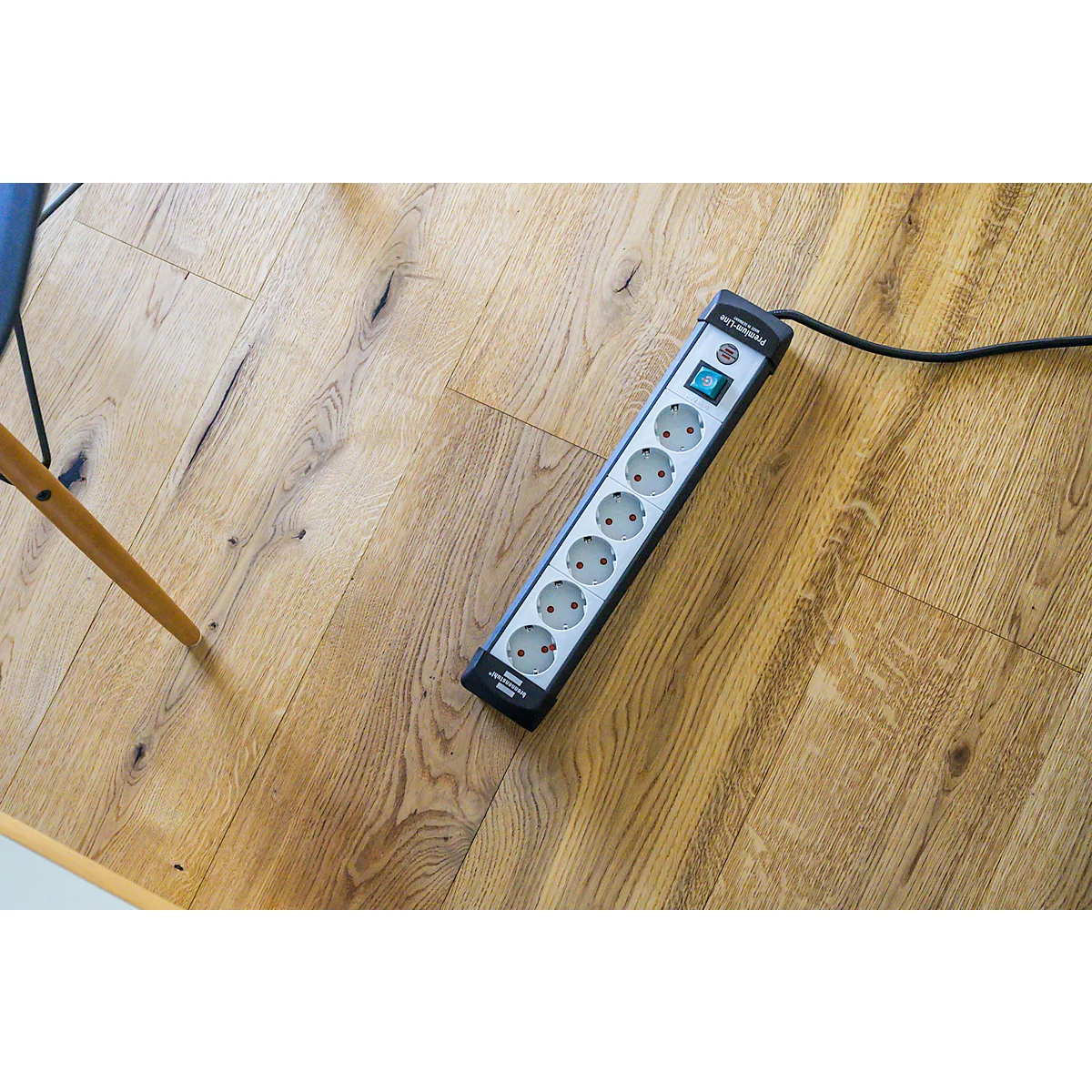 Multiprise sur plancher en bois. Câble d'alimentation branché.