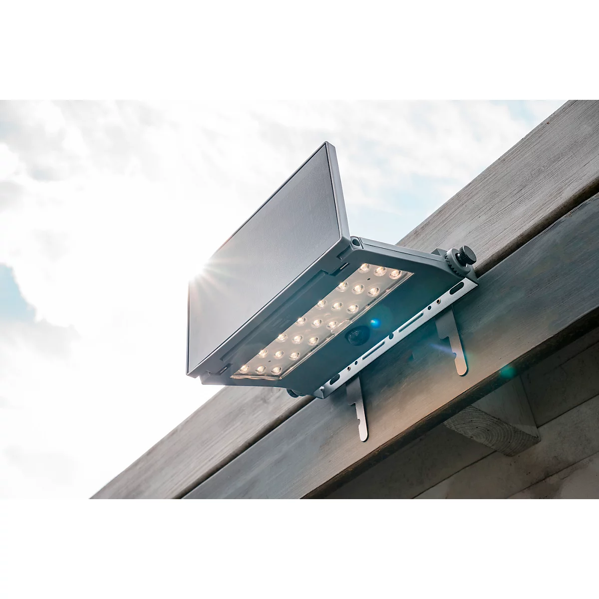 Een solar LED-verlichtingsarmatuur bevestigd aan een houten frame. De zon schijnt op de achtergrond.
