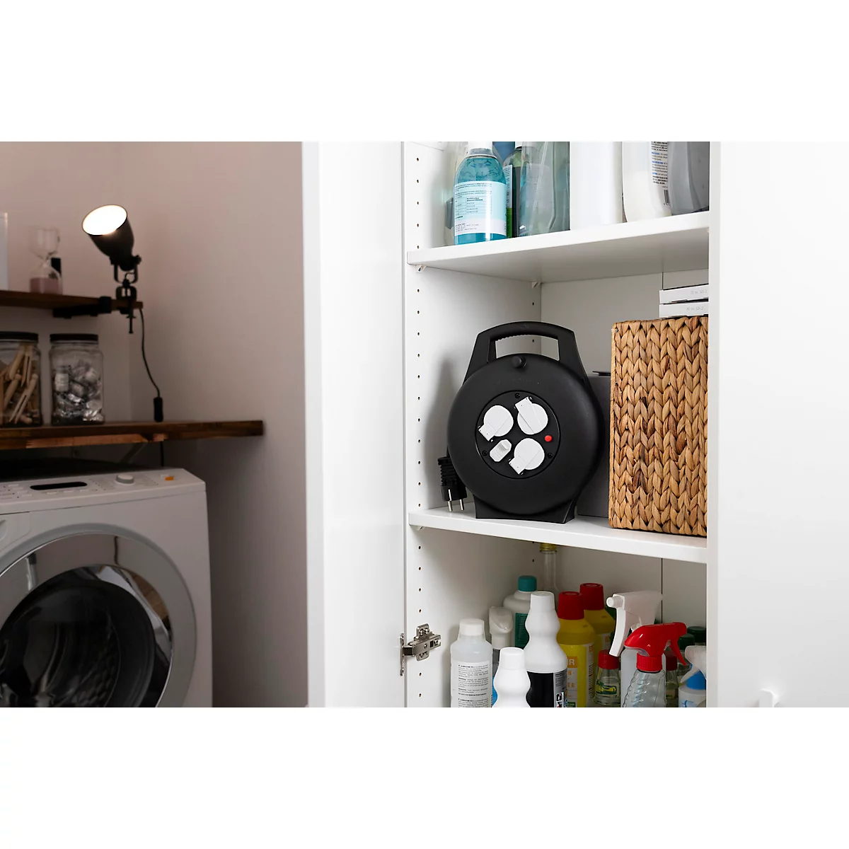 Nahaufnahme einer schwarzen Kabeltrommel mit vier Steckdosen, teilweise geöffneten Klappen und rotem Knopf.