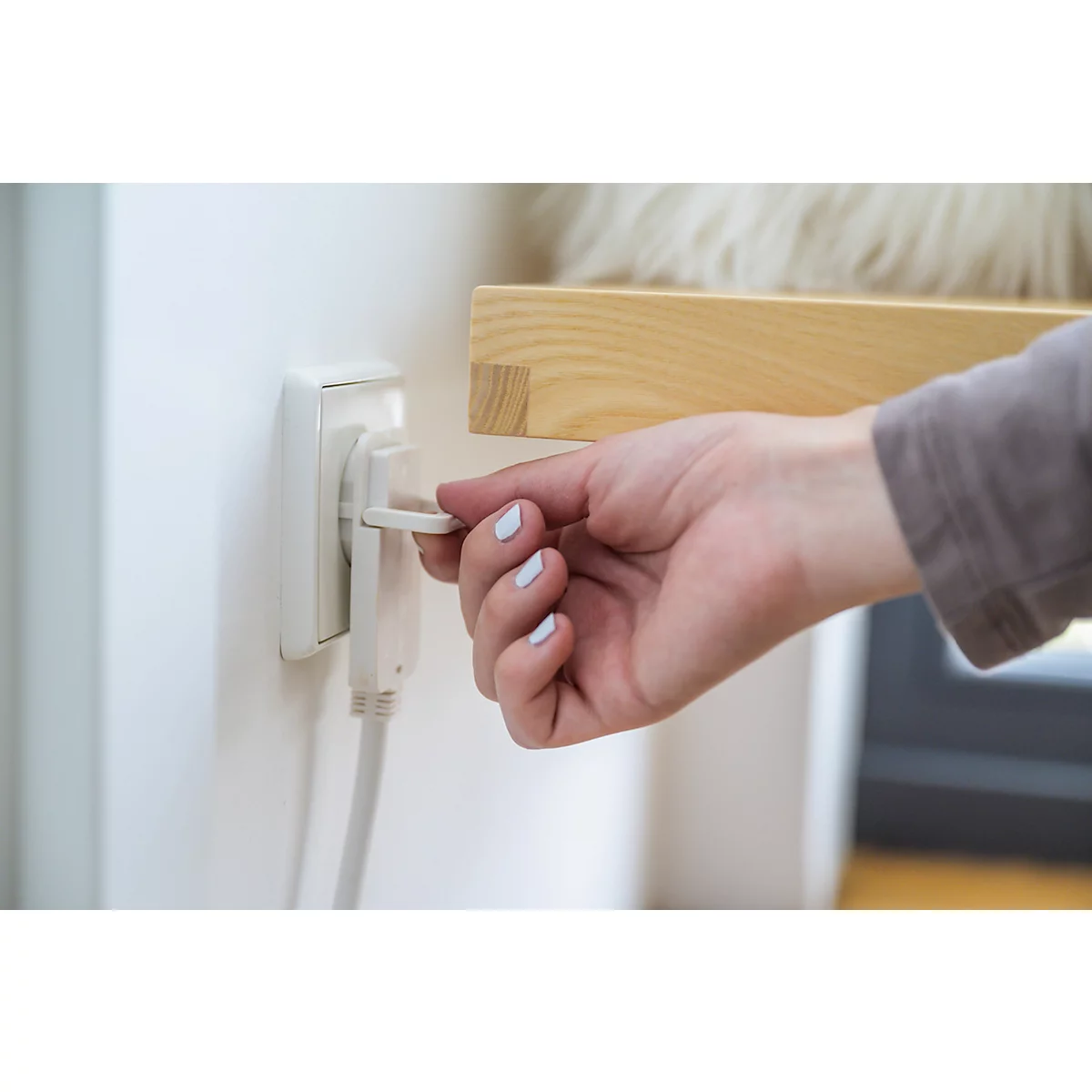 Nahaufnahme: Person steckt einen schwarzen Stecker in eine weiße Steckdose.