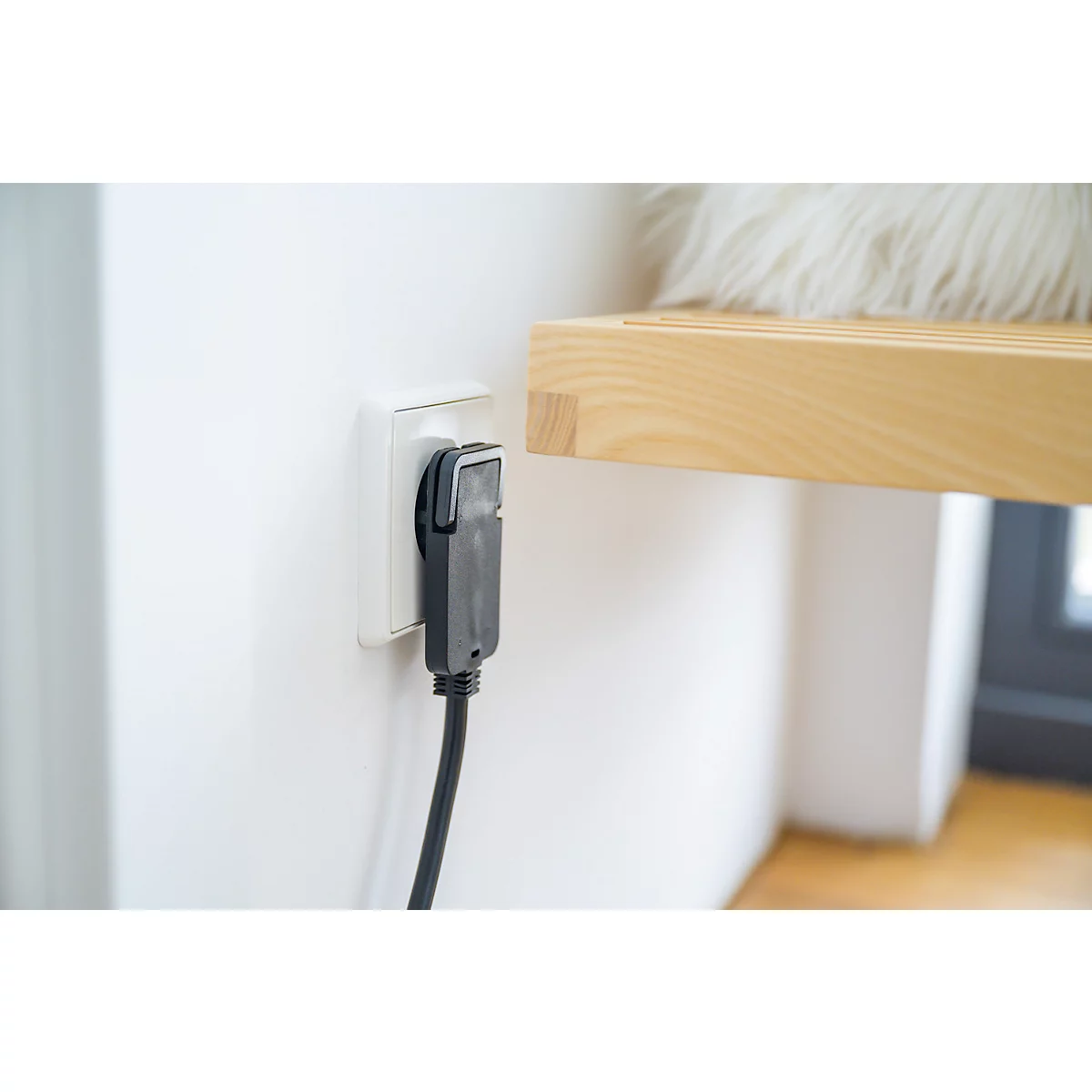 Ein schwarzer gewinkelter Stecker mit zwei runden Stiften und einem schwarzen Kabel.