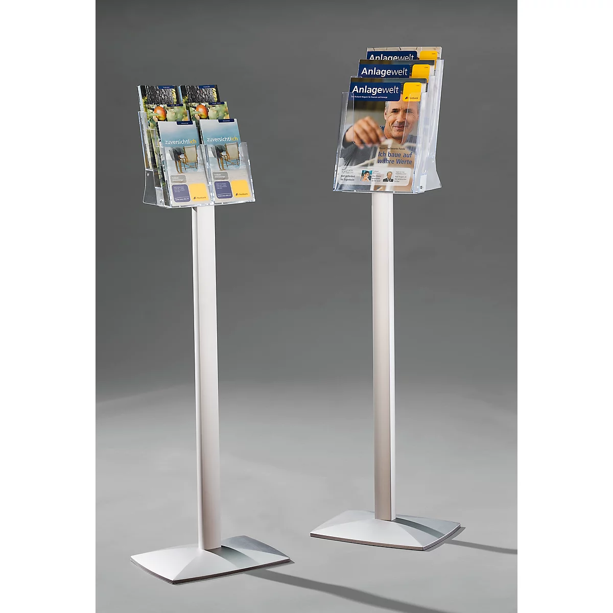 Two silver brochure stands with brochures in plastic compartments. One says "Anlage Welt".