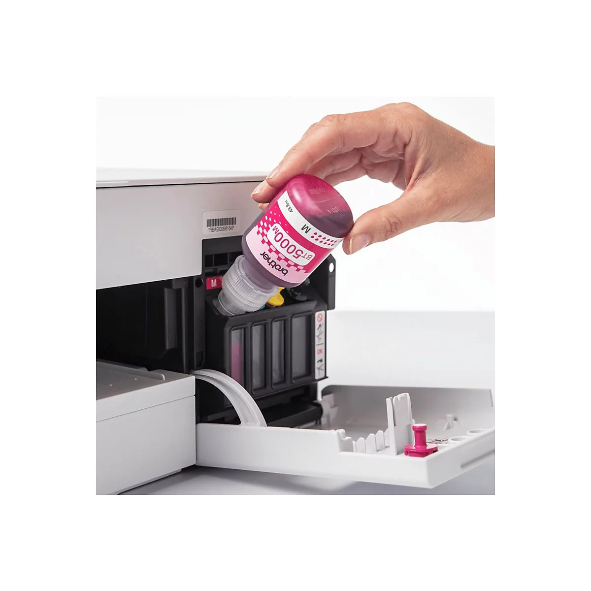 Eine Hand füllt magenta Tinte in einen Drucker. Die Flasche ist mit BT5000M beschriftet.