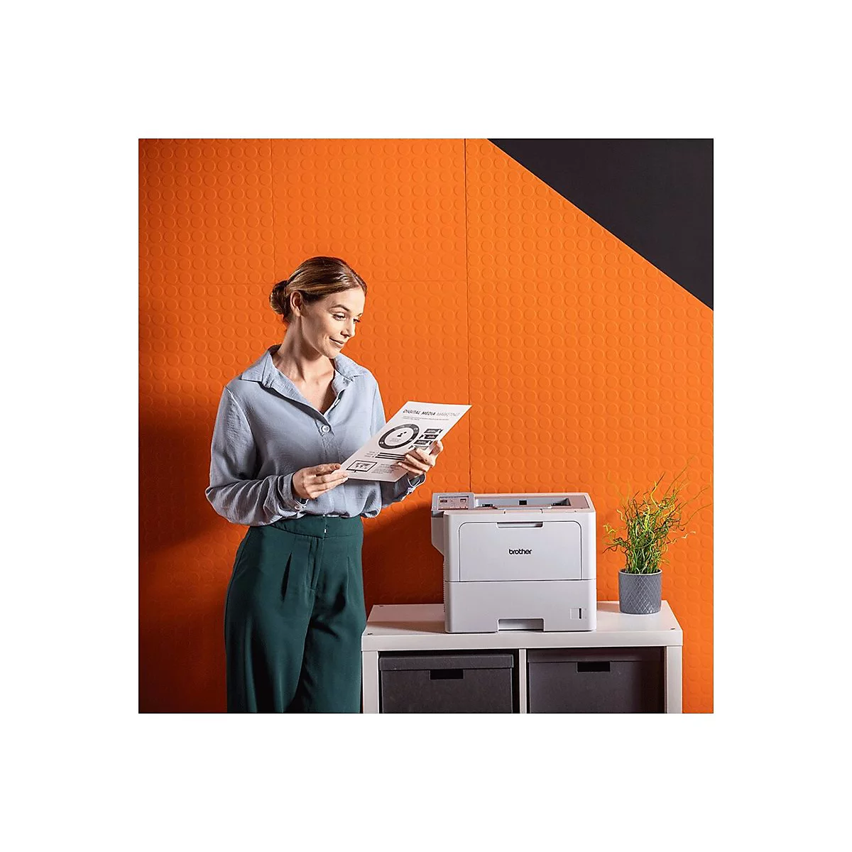 Frau betrachtet Dokument neben Drucker. Aufdruck 'Digital Marketing'. Hintergrund: orange Wand mit Kreisen.