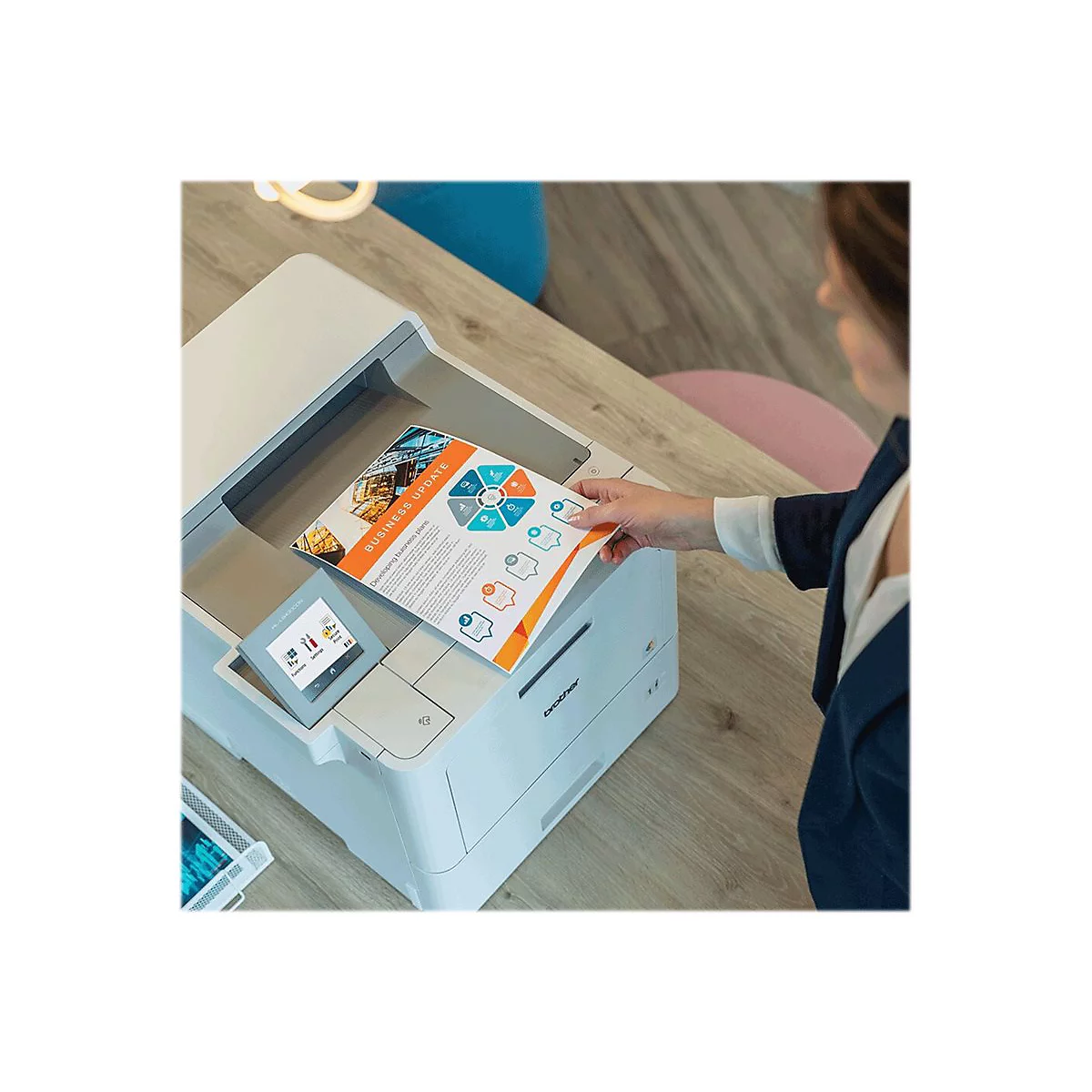 Eine Person entnimmt ein gedrucktes Papier mit "Business Update" aus einem Brother-Drucker. Auf dem Bildschirm ist ein Menü zu sehen.