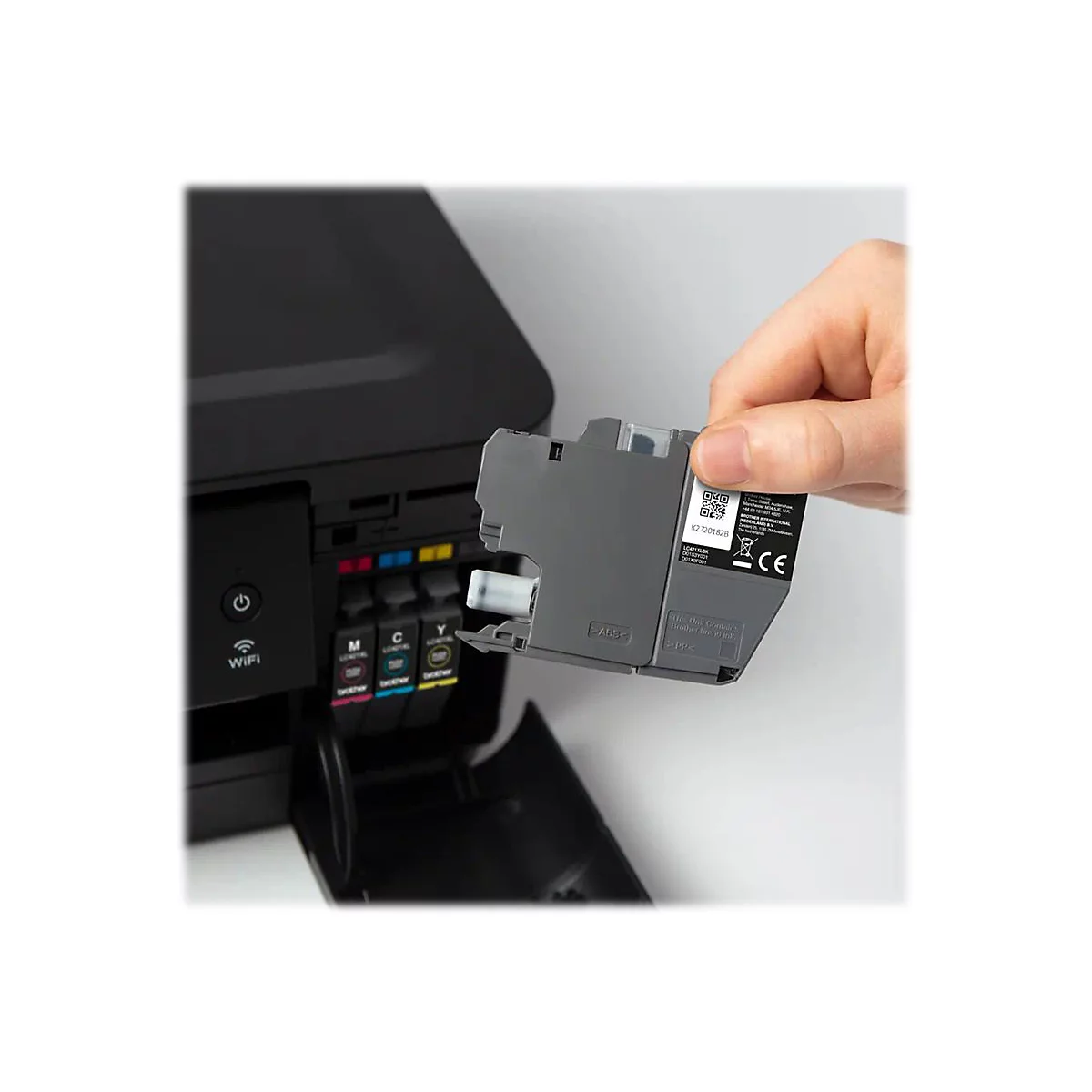Eine Hand hält eine Druckerpatrone, die in einen schwarzen Drucker eingesetzt wird. Der Drucker ist teilweise geöffnet.