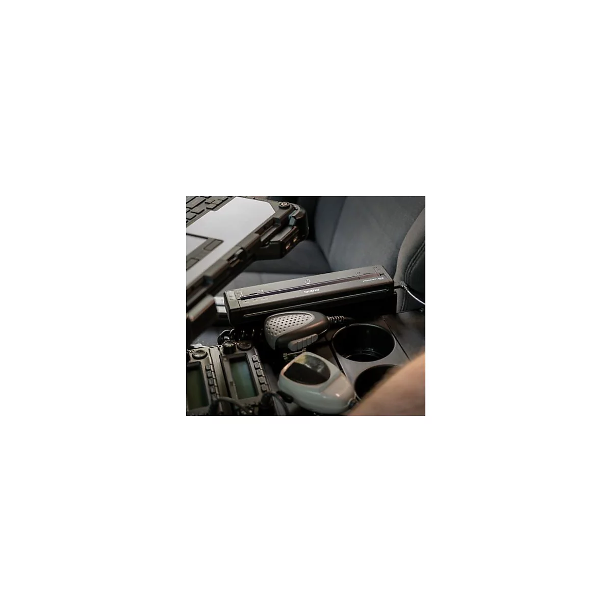 Szene im Auto: Scanner, FunkgerÃ¤te und Laptop auf der Mittelkonsole. Mikrofone und Becherhalter ebenfalls sichtbar.