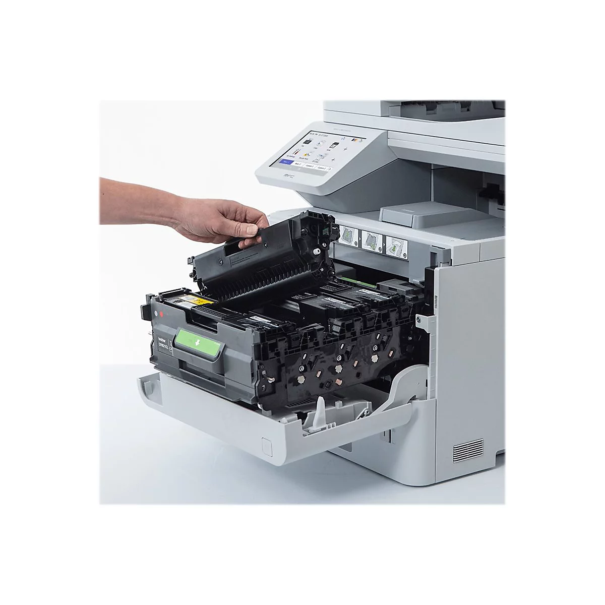 Hand hält eine Tonerkartusche über einem Drucker. Geöffnete Klappe mit weiteren Kartuschen.
