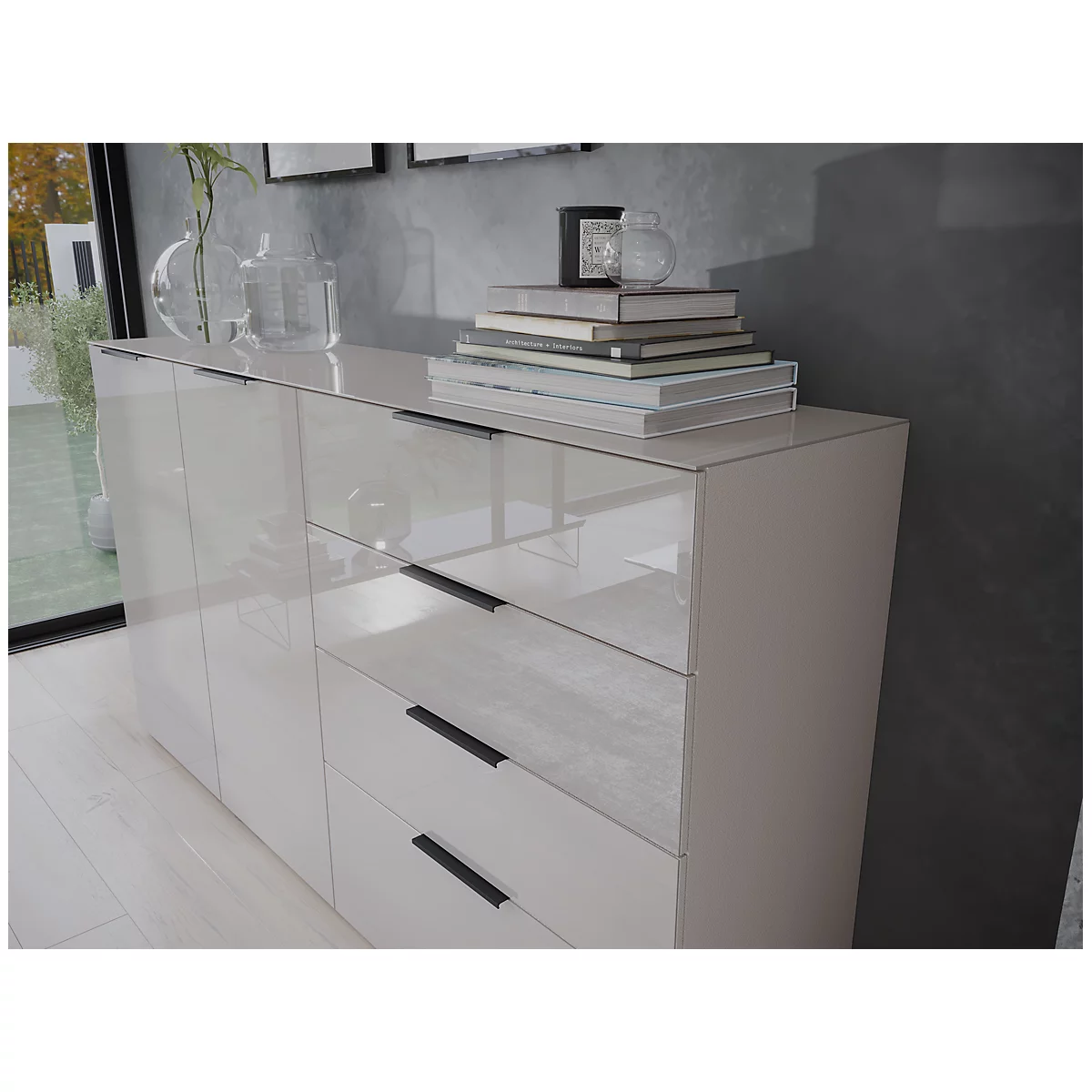 Un buffet crème brillant, avec des livres et de la décoration dessus. Poignées noires sur les tiroirs et les portes. En arrière-plan, des fenêtres avec vue sur l'extérieur.
