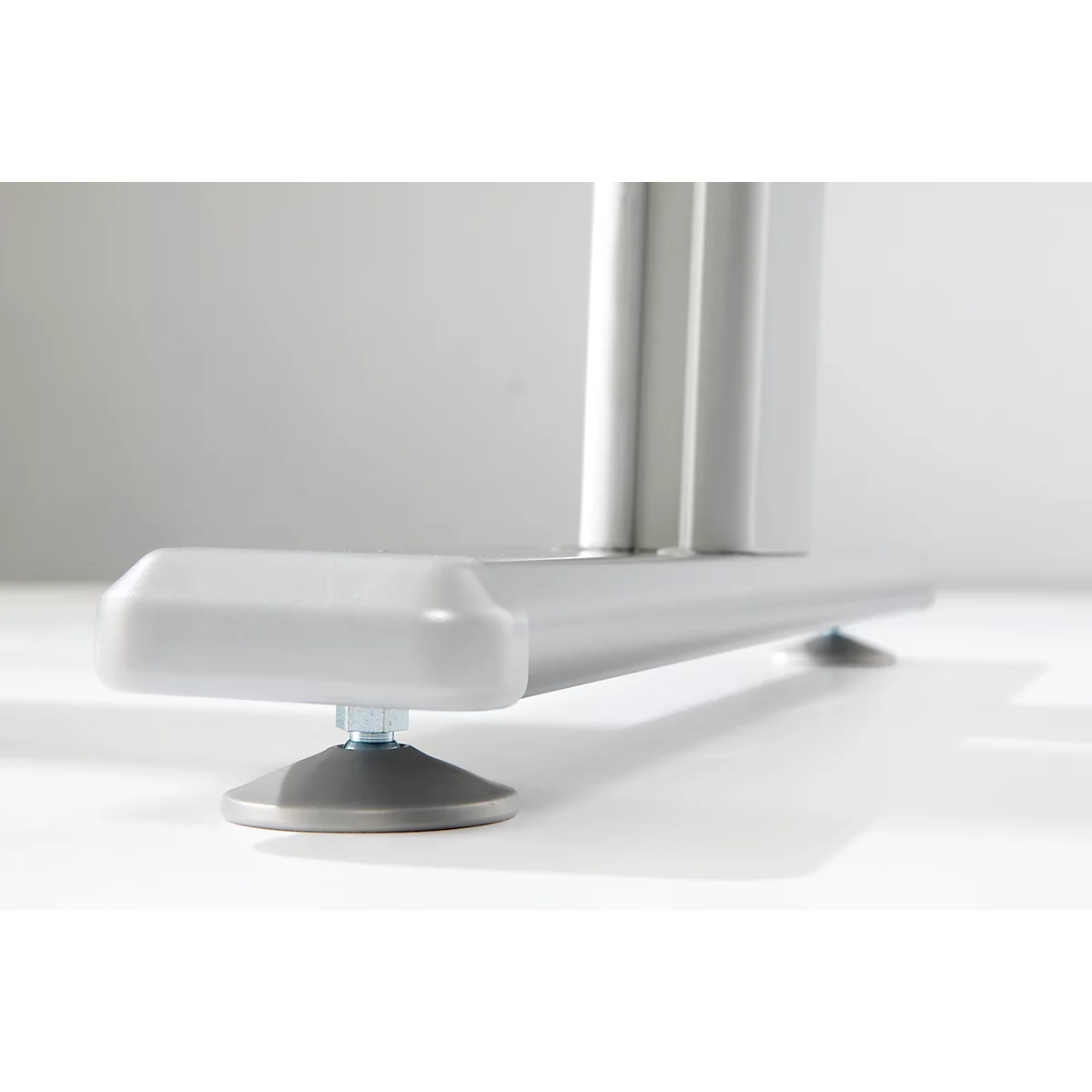 Gros plan : un pied de table gris avec un pied réglable. Le pied se compose d'une base ronde noire et d'une vis.